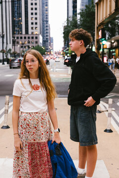 Two teenagers waiting on a busy city street corner
