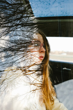 Pensive young woman with reflection of trees