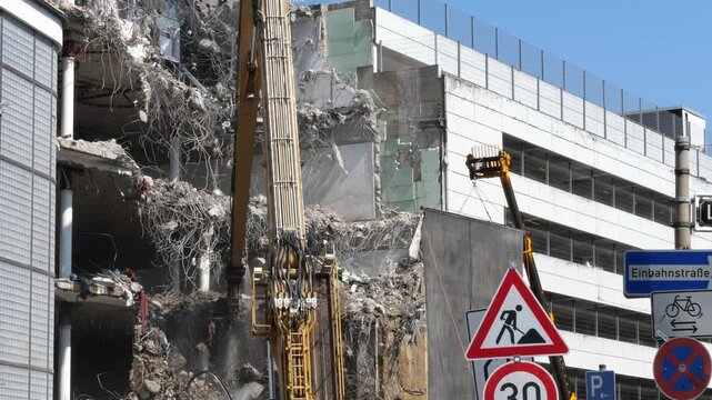 Demolition Excavator Boom Arm Tearing Down Concrete Structure of Multilevel Building Under Clear Blue Sky
