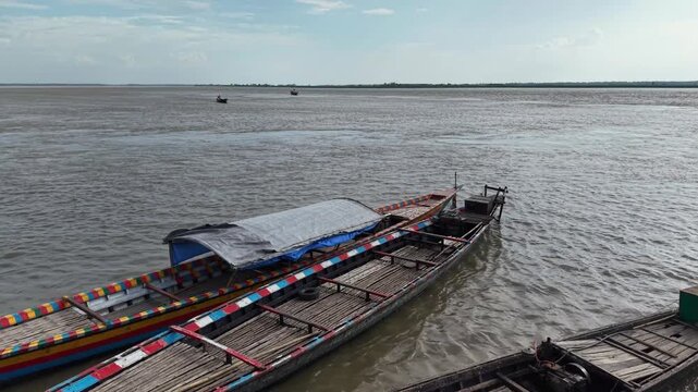Traditional wooden longtail boats moored on a wide tropical river at sunset