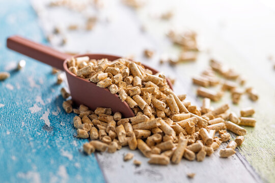 Close-Up Scoop of Wood Pellets Spilled on Table for Biomass Fuel and Sustainable Heating