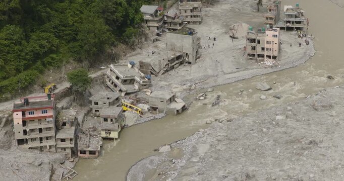 Aerial shot of Nuwakot, Nepal, of extensive flash flood disaster damage, with collapsed residential buildings and heavy silt accumulation along eroded riverbanks following a glacial outburst