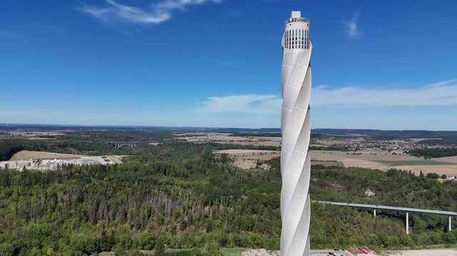 A steady close aerial approach reveals surface details of the Rottweil elevator test tower, with woodland visible behind the structure.