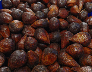 Close-up of fresh salak fruits, known as snake fruit, with scaly brown skin. Piled tropical produce displayed at a market, perfect for healthy food themes. © Regi