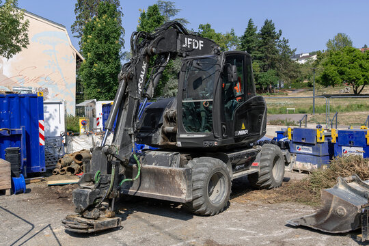 Nancy, France - July 25th 2026 : View of a 15-tonne black compact wheeled excavator Mecalac 15MWR on a construction site for work on the drinking water network.