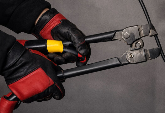 Person using bolt cutters with protective gloves for cutting tasks
