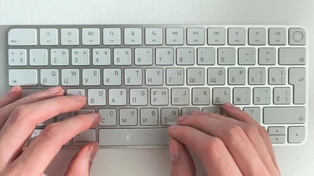 Hands typing on computer keyboard from a first person perspective look. Employee works on an internet project or educational assignment from an overhead angle. Flat lay design frames desktop