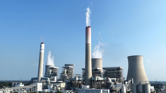 Power plant with cooling towers and smokestacks under blue sky