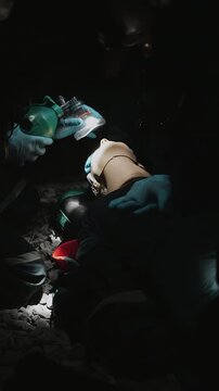 Rescue team practices emergency respiratory care on a training mannequin using a manual resuscitation bag and mask during a first aid exercise.
