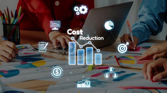 A business team collaborates in a modern office to analyze data and discuss cost reduction strategies, using charts and technology to enhance decision-making. Raster