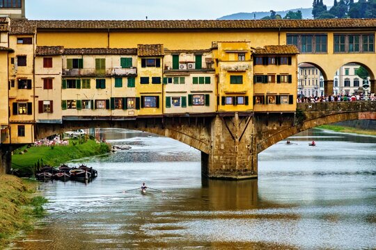 View of the historic Ponte Vecchio bridge with its iconic yellow buildings spanning the Arno river in Florence, Tuscany, Italy.