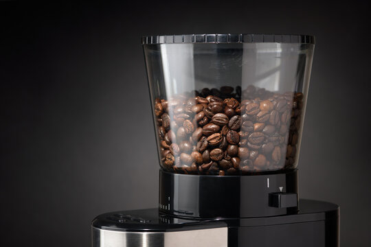 Roasted coffee beans filling grinder hopper, preparing fresh brew