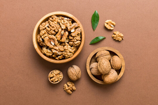 Walnut kernel halves, in a wooden bowl. Close-up, from above on colored background. Healthy eating Walnut concept. Super foods with copy space