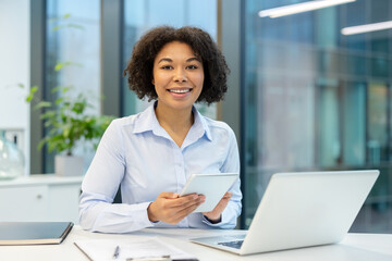 Obraz premium Professional woman working in office, corporate employee using digital tablet and laptop for business communication and productivity