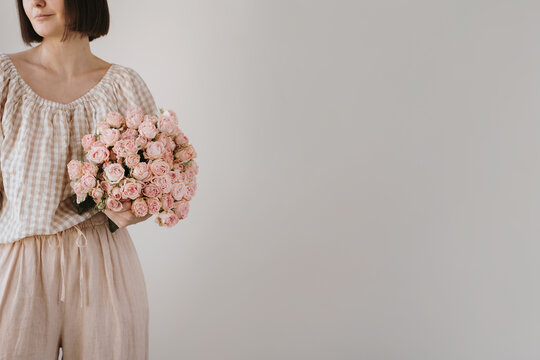 Woman wearing cozy top creating romantic pose with fresh pink roses bouquet. Ads, banner mockup