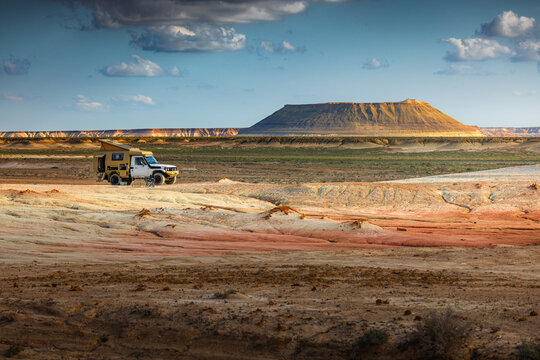 View of the striped, layered rock formations of Kyzyl Kup, known as Tiramisu, with an off-road camper parked in the arid desert landscape in Karakiya District, Mangystau Region, Kazakhstan.