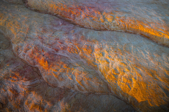 View of the colorful, layered, and cracked sedimentary rock formations of Kyzyl Kup, known as Tiramisu, in the warm golden hour light of Karakiya District, Mangystau Region, Kazakhstan.
