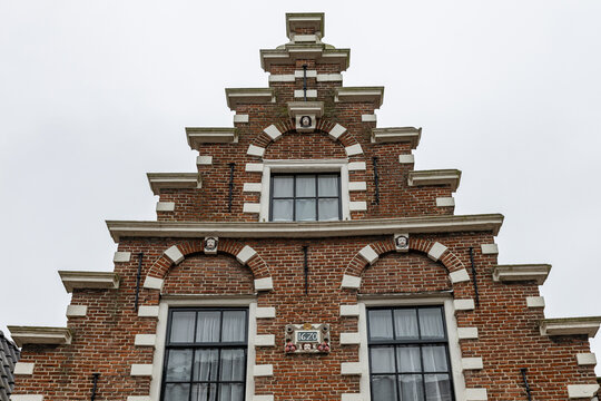 View of a historic Dutch brick house with a stepped gable, white stone accents, and a 1620 date stone in Monnickendam, North Holland, Netherlands.