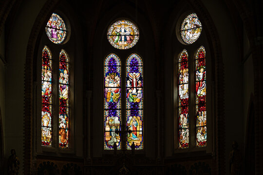 View of intricate stained glass windows depicting religious scenes inside a historic church in Monnickendam, North Holland, Netherlands.