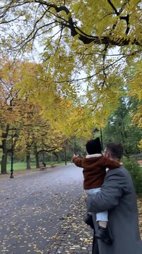 Father holding son in autumn park