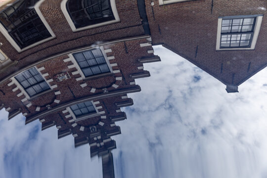 View of the reflection of a traditional Dutch brick building with a stepped gable in the water in Monnickendam, North Holland, Netherlands.
