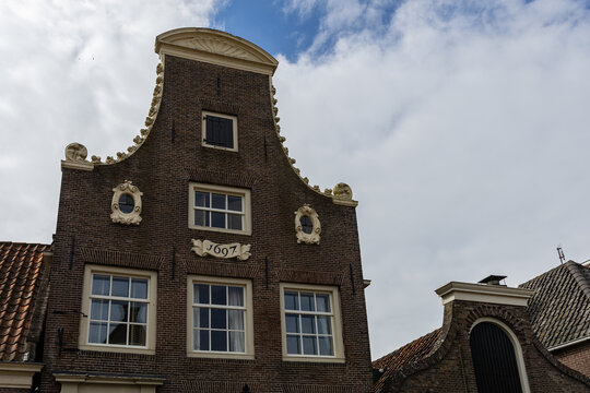 View of a historic brick house facade with a decorative stepped gable and the year 1697 inscribed on the front in Monnickendam, North Holland, Netherlands.