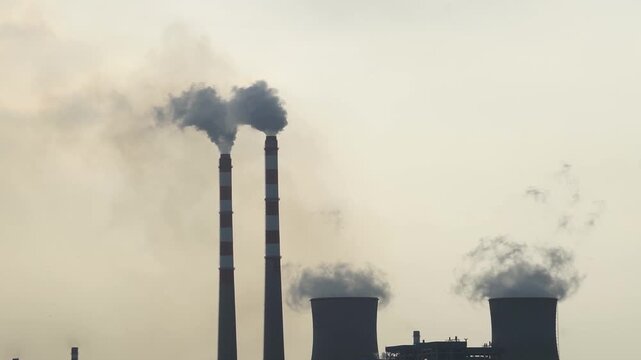 Tall chimneys of the power plant billowing thick smoke