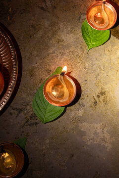 View of traditional oil lamps glowing on green leaves during a ceremony in Kathmandu, Bagmati Province, Nepal.