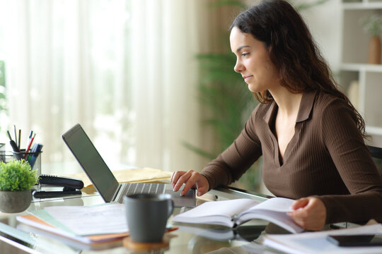Young telecommuter checking laptop and agenda at home