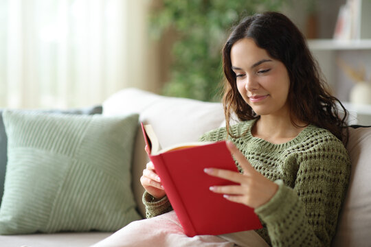 Young woman reading paper book in winter at home