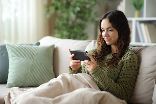Young woman watching media on phone in winter