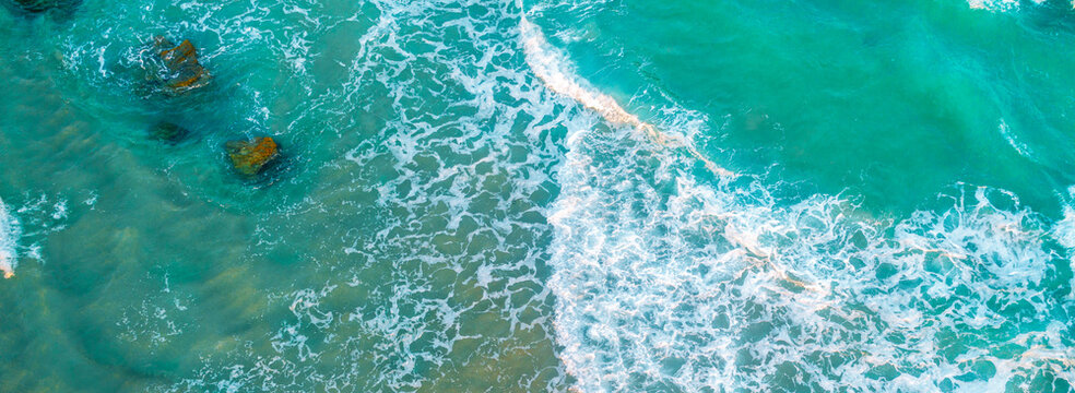 Top view of ocean waves rolling on the beach