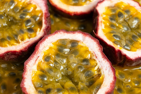 Halved passion fruit slices placed over juicy fruit pulp background