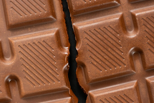 Broken milk chocolate bar with geometric line pattern, texture macro background