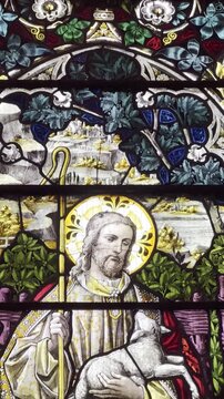 Historic stained glass church window depicting Jesus Christ as the Good Shepherd with sheep, colorful religious art, Gothic arch design, Christian heritage, sacred architecture and spiritual symbolism
