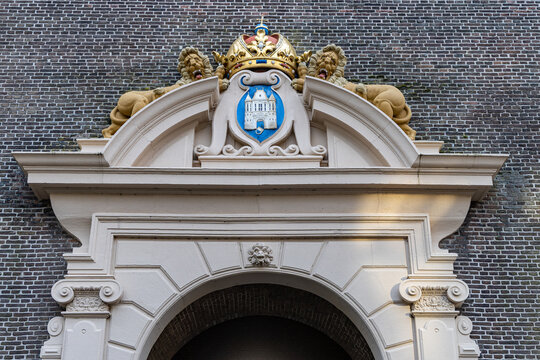 View of the historic stone archway featuring the ornate coat of arms of Kampen with a crown and lions set against a brick wall in Kampen, Overijssel, Netherlands.