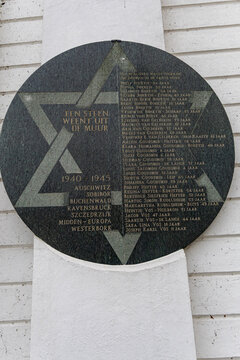 View of the Joods Monument Kampen, a circular stone plaque featuring a Star of David and a list of names, mounted on a white wall in Kampen, Overijssel, Netherlands.