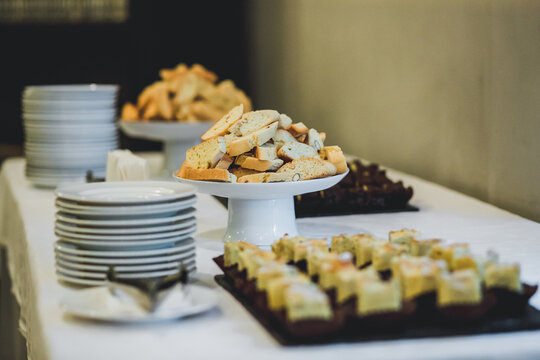 Assorted desserts and crispy biscotti crackers on dessert table at catering event.