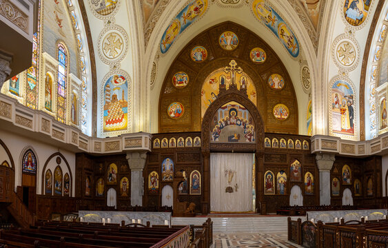 View of the ornate interior of a Coptic church featuring intricate wood carvings, religious icons, and colorful stained glass windows in Cairo, Cairo Governorate, Egypt.