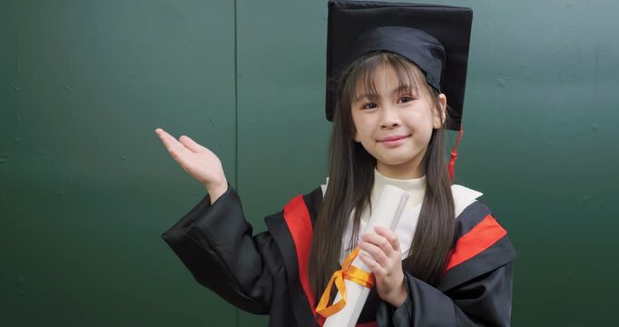 Asian graduate girl holding diploma scroll presenting with palm open to copy space.