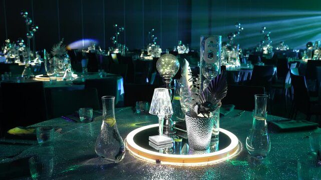 Elegant table setting with illuminated centerpieces and decorative glassware, showcasing a sophisticated dining atmosphere in a modern event space with ambient lighting