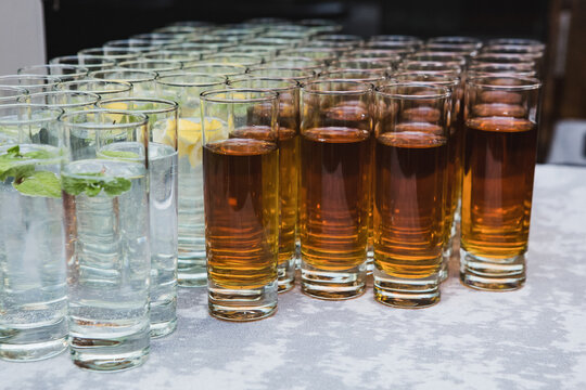 Rows of refreshing cold lemonade with mint and fresh apple juice prepared for catering welcome bar.
