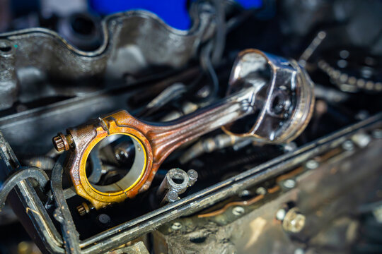 Piston and connecting rod removed from disassembled car engine. Engine overhaul and piston inspection represent diagnostics, wear and automotive repair