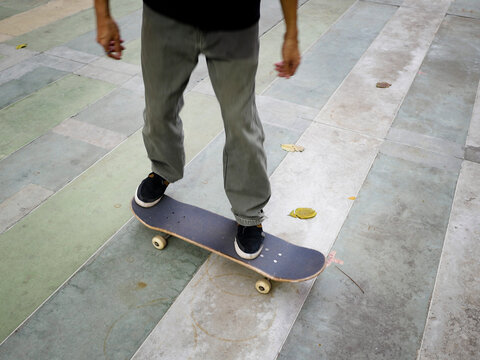 A male skateboarder with a black shirt doing a kickflip on a skateboard on a cloudy day in Thailand