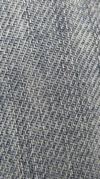 Extreme macro close-up video showing the detailed weave and texture of blue denim jeans fabric.
