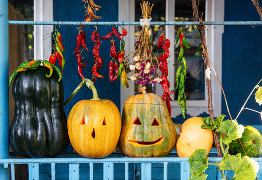 Rustic Homemade Halloween Decoration with Carved Pumpkins and Peppers, red and green chili peppers, dried flowers, and autumn foliage.