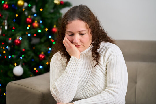 Sad, couch and woman in home on christmas with crying for depression, loneliness or hopeless. Mental health, holidays and person with tears and emotions for alone on xmas in living room at apartment.