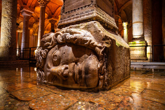 Ancient stone column base with Medusa head sculpture inside the Basilica Cistern, Istanbul, Turkey, illuminated by soft lighting