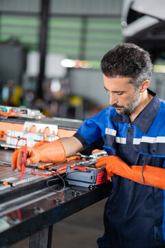 An electric vehicle battery module is tested by a technician resting both probes of an insulation tester on the open pack.
