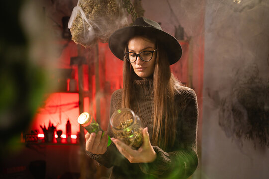 A realistic witch brewing a potion in a cauldron. holds a jar of ingredients and is selecting the one she needs. Everyday life intertwined with traditional witchcraft, magic, and a mystical atmosphere